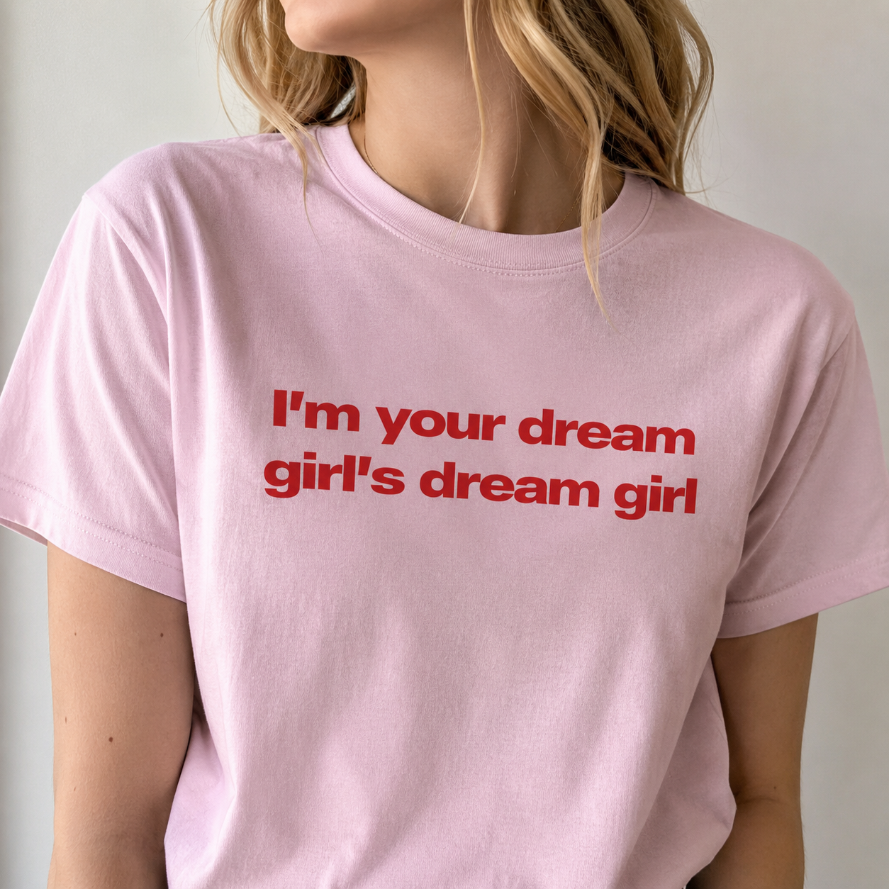 Person wearing a pink t-shirt with red text on a plain background