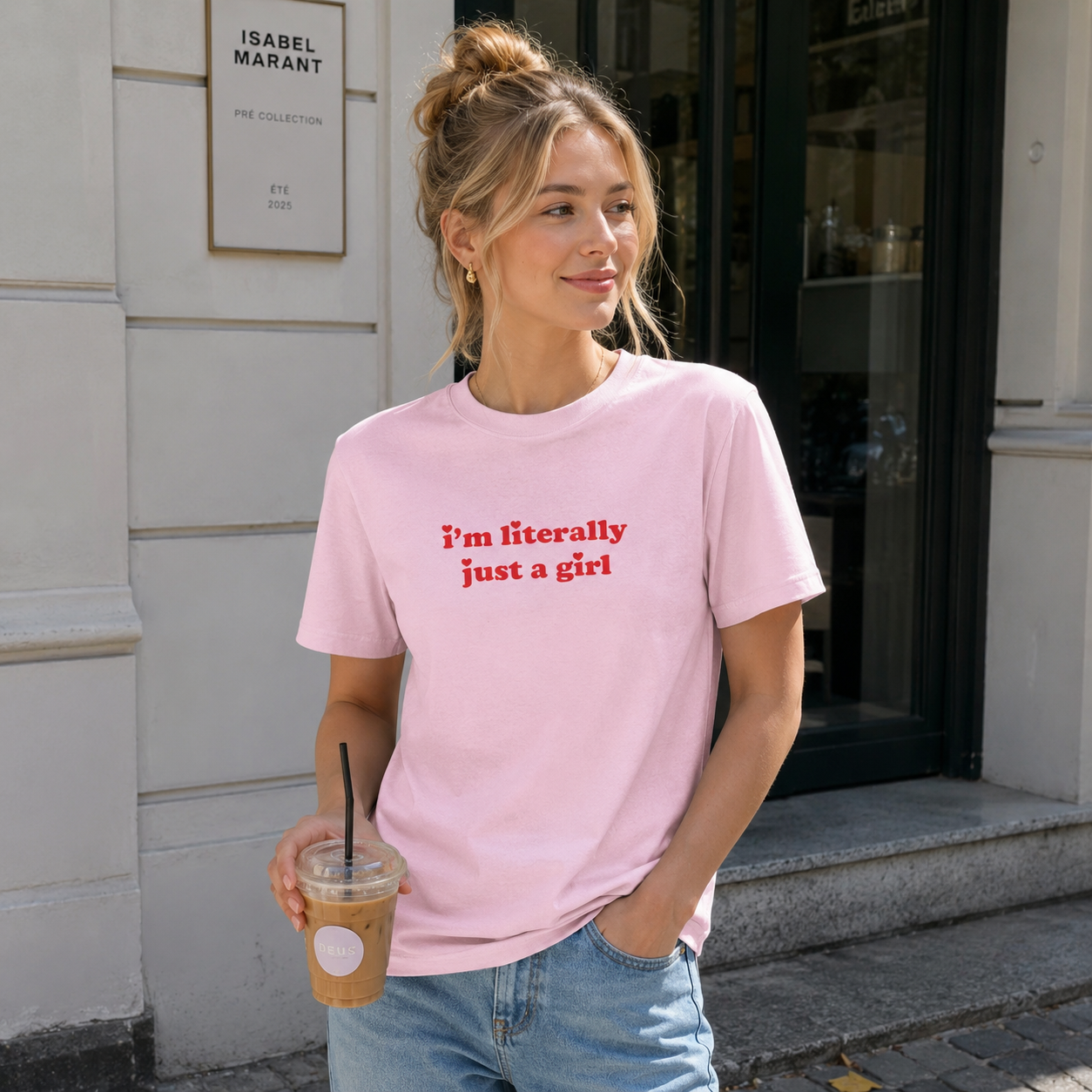 Woman wearing a pink t-shirt with text, standing on a street.