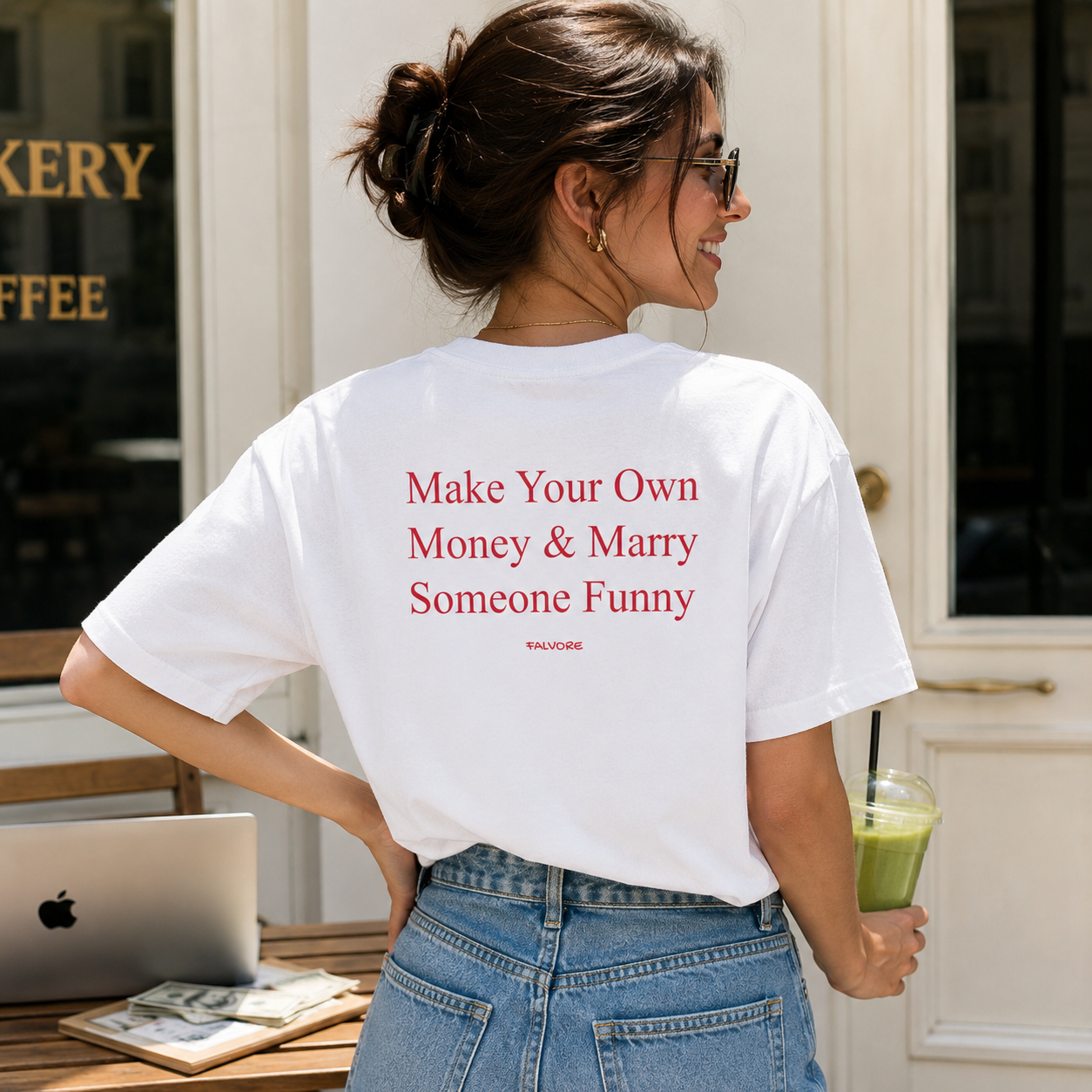 Woman wearing a white t-shirt with red text in front of a bakery.