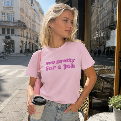 Woman wearing a pink t-shirt with text, standing on a city street.