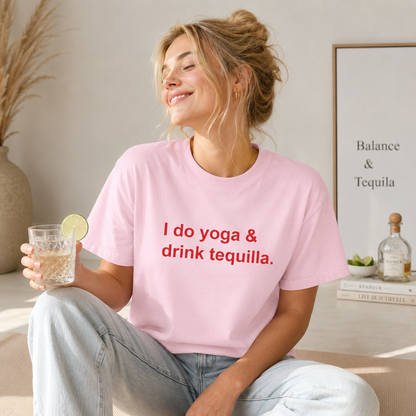 Woman wearing a pink t-shirt with text, holding a glass of water with a lime, in a casual setting.